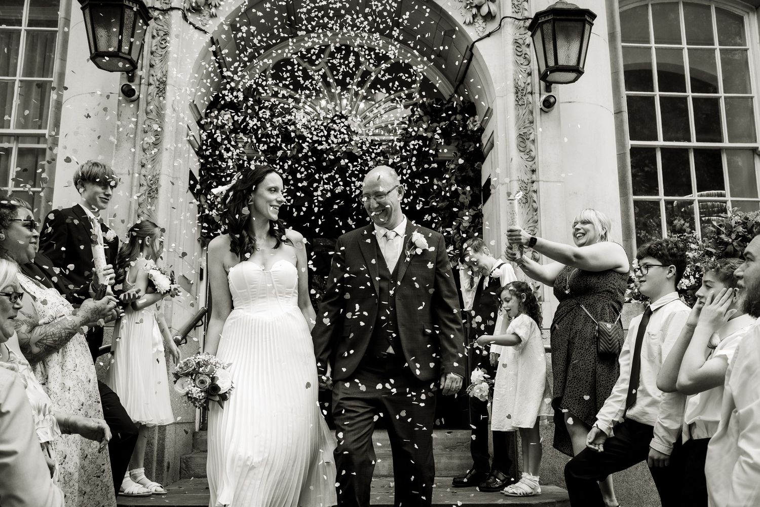 Black and white confetti canon shot of bride and groom at Chelsea Old town hall