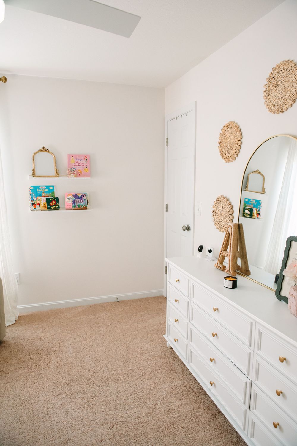 White nursery room with built-in storage cabinets and decorative wall accents.