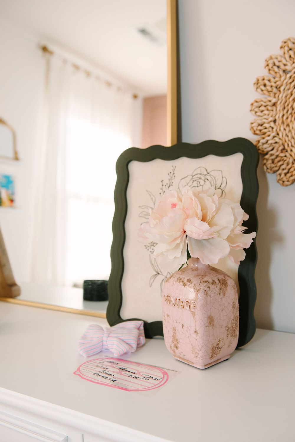 Delicate pink floral arrangements in decorative frames displayed on a white shelf with soft lighting.