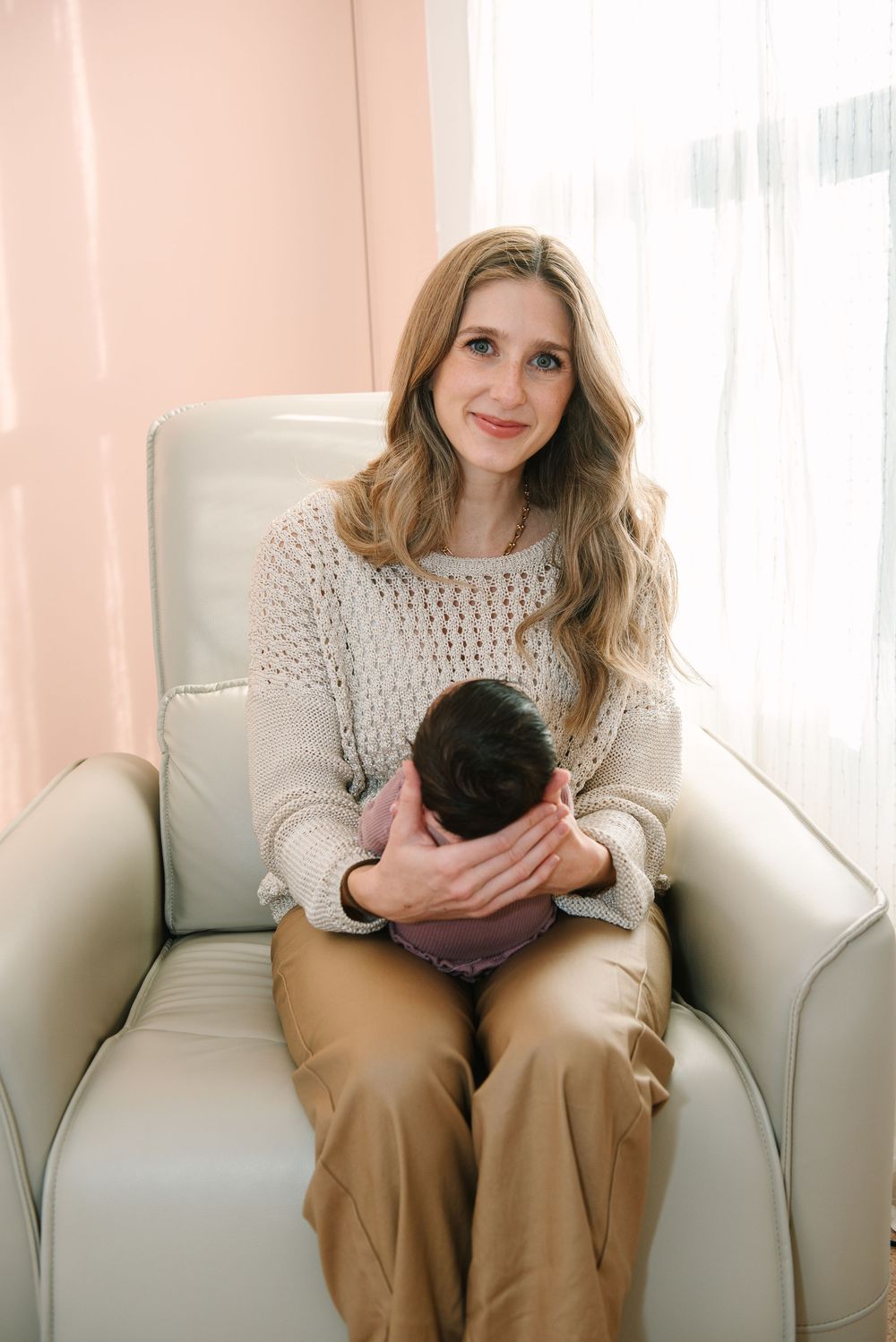 A cozy scene on a cream-colored couch with soft pink walls and natural window light.