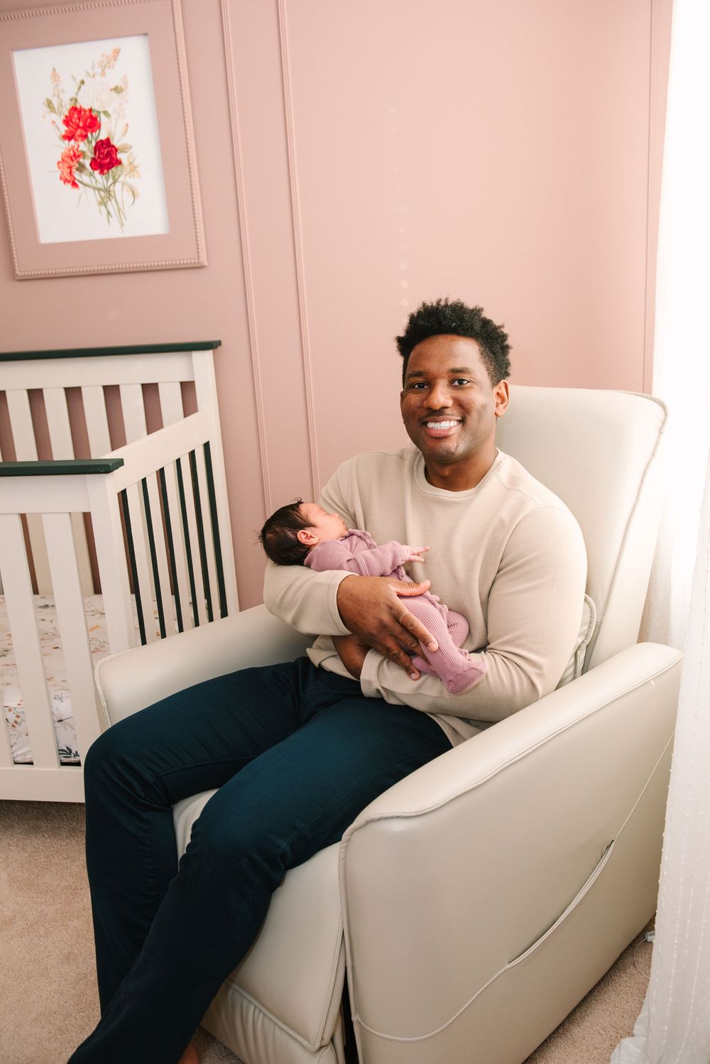 Sweet family bonding moment in a nursery with pink walls and floral artwork.