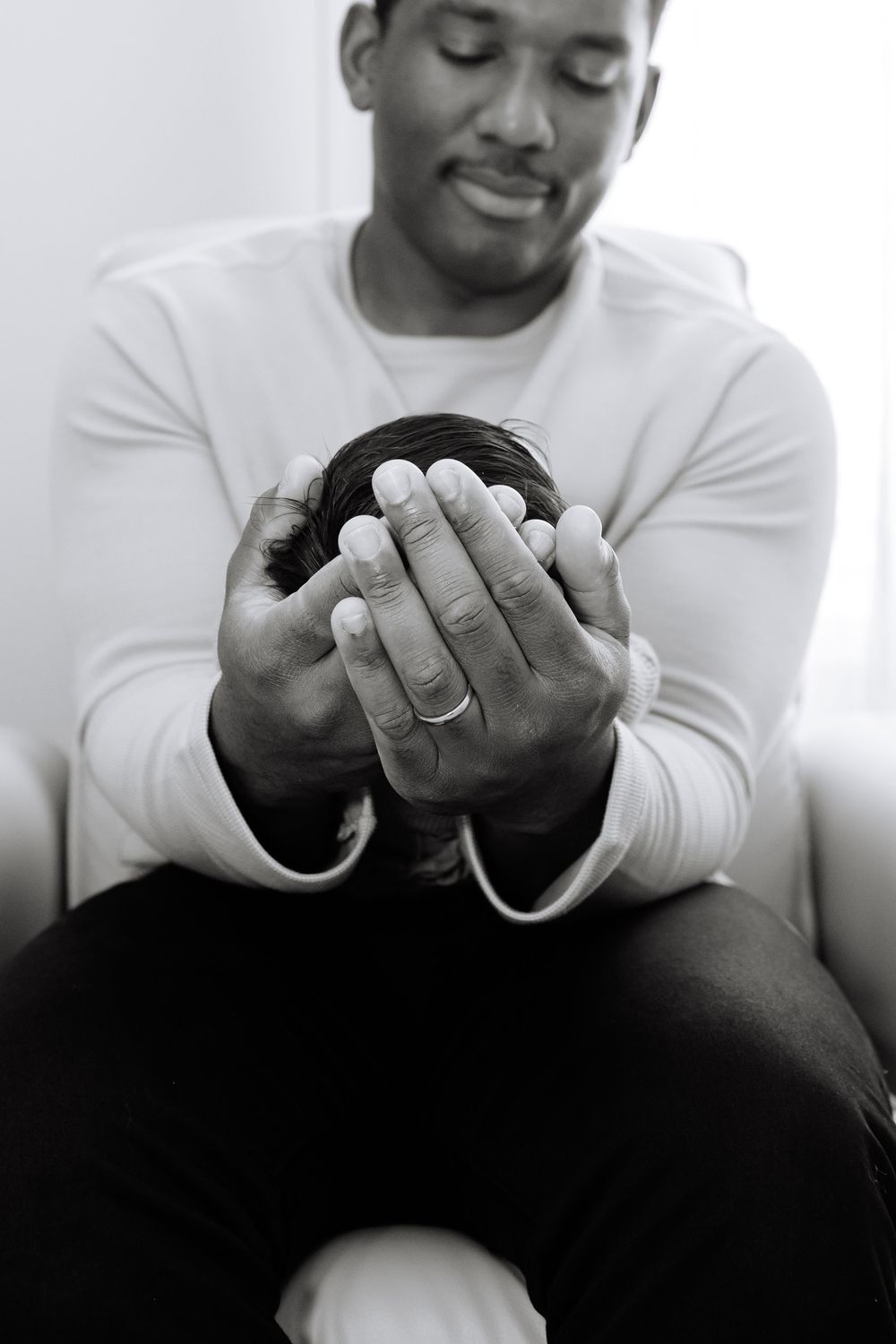 A sequence of black and white photos showing hands holding and examining a small object in white clothing.