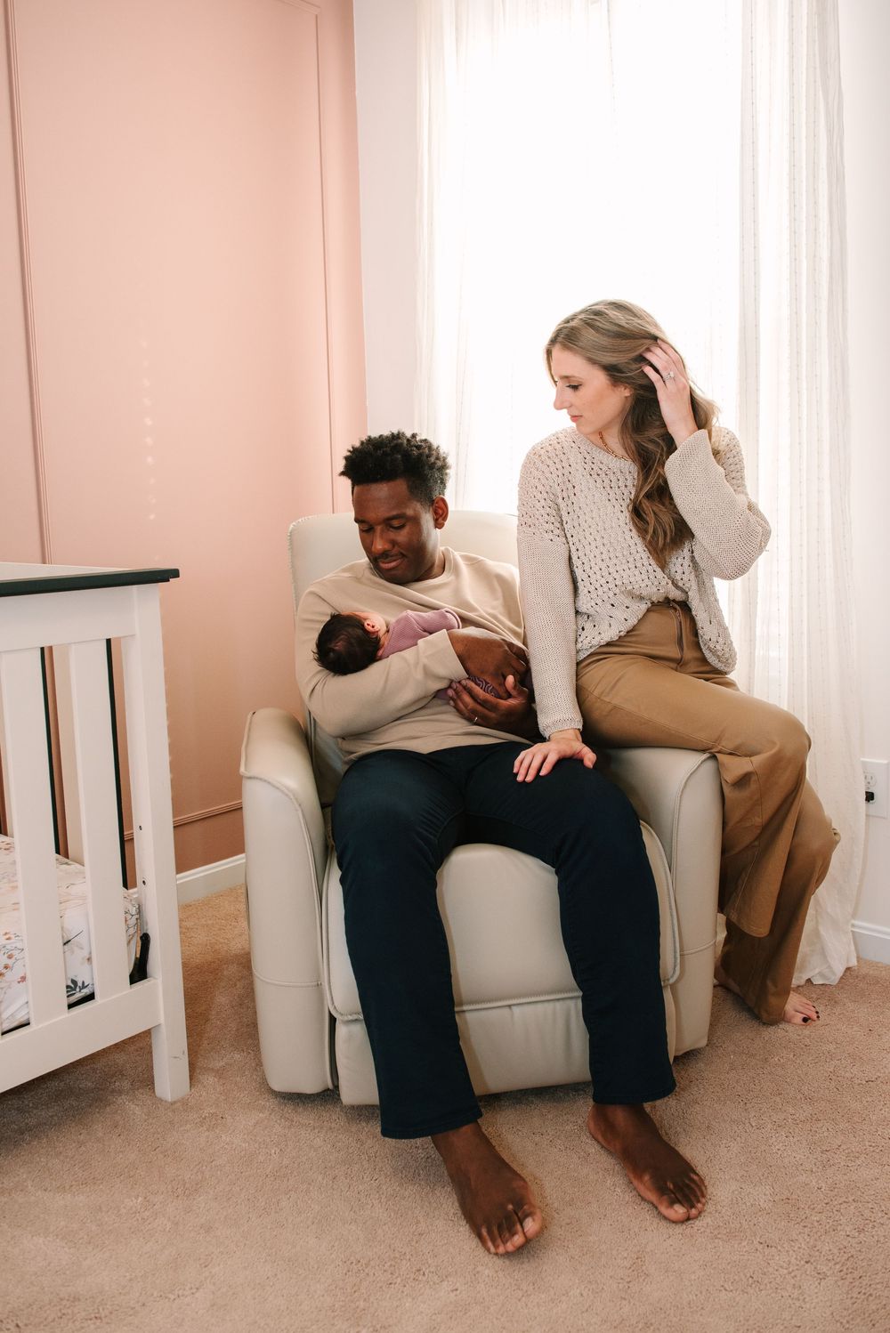 Intimate moments captured on a light gray sofa against blush pink walls.