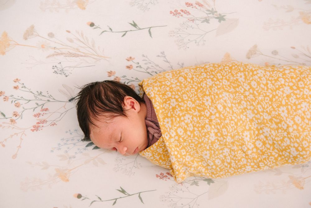 Child sleeping peacefully on floral yellow bedding in natural light.