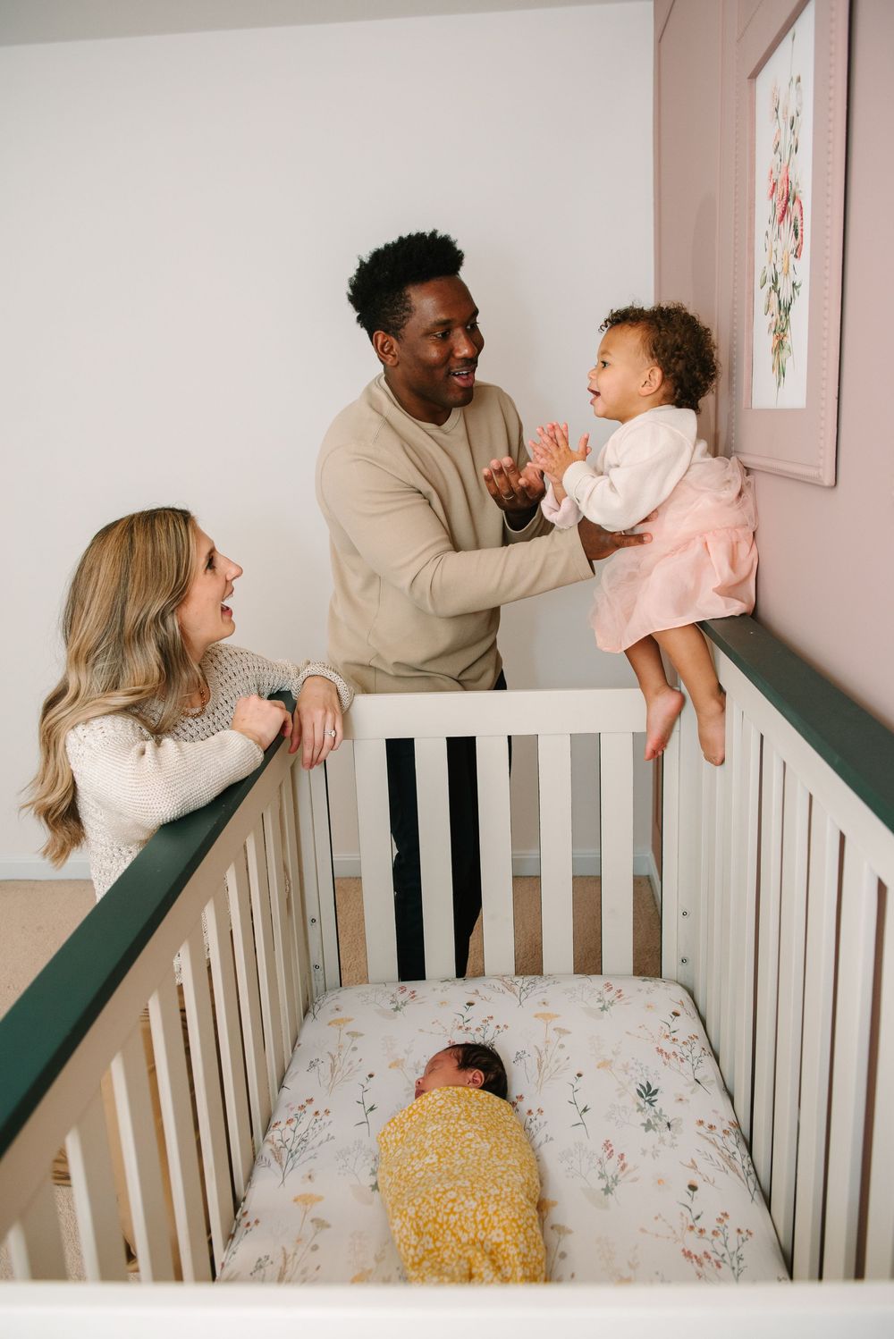 A series of photos showing playful family moments with a baby in a white crib with floral bedding and pink decor.