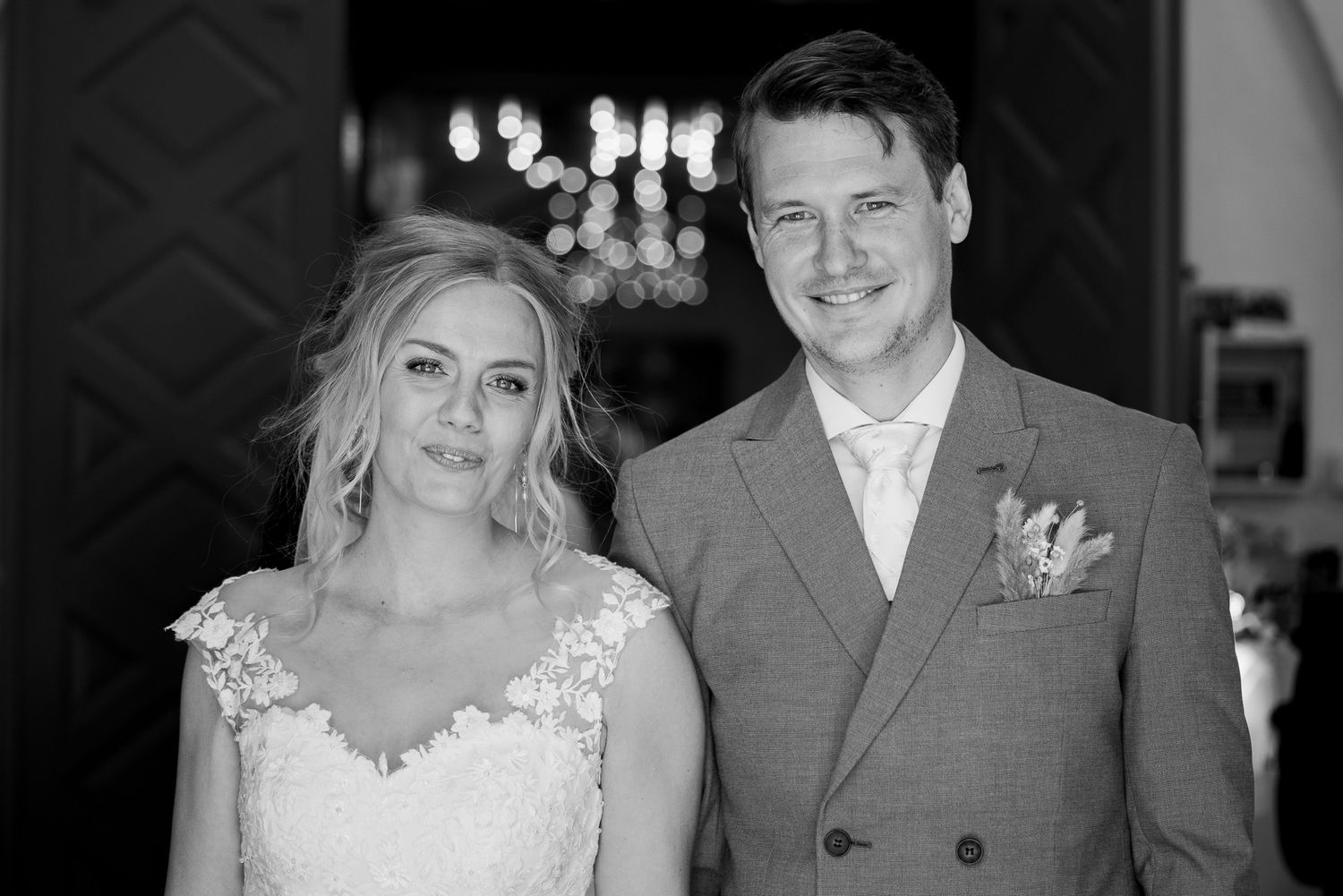 Elegant wedding portrait in black and white with chandelier backdrop.