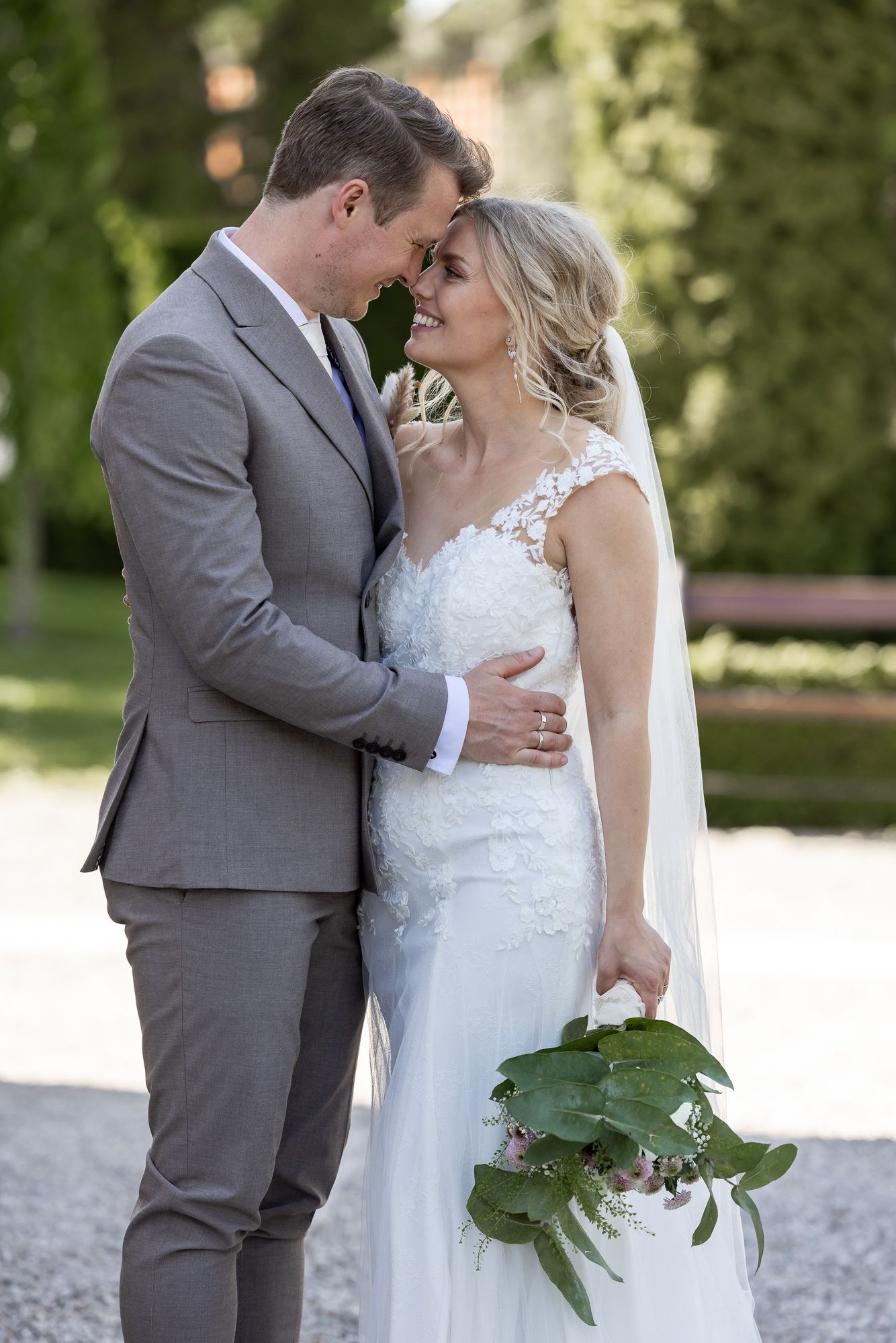 Intimate wedding portrait with couple sharing tender moment in garden setting.