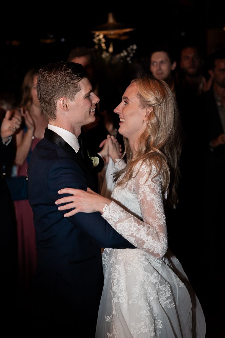 Couple sharing their first dance at wedding reception in dark romantic lighting.