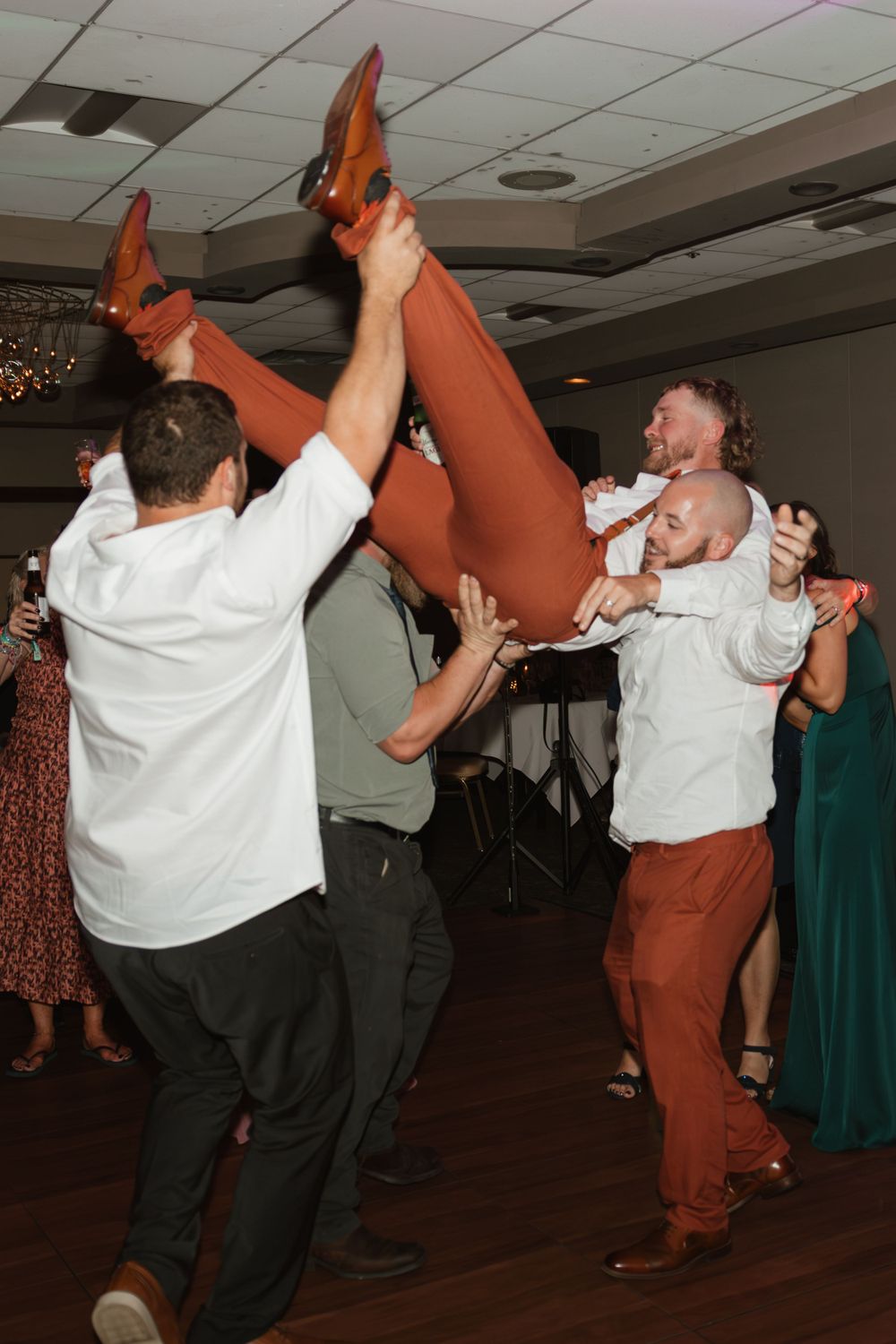 Energetic group dance moves at wedding reception with guests in coordinated outfits.