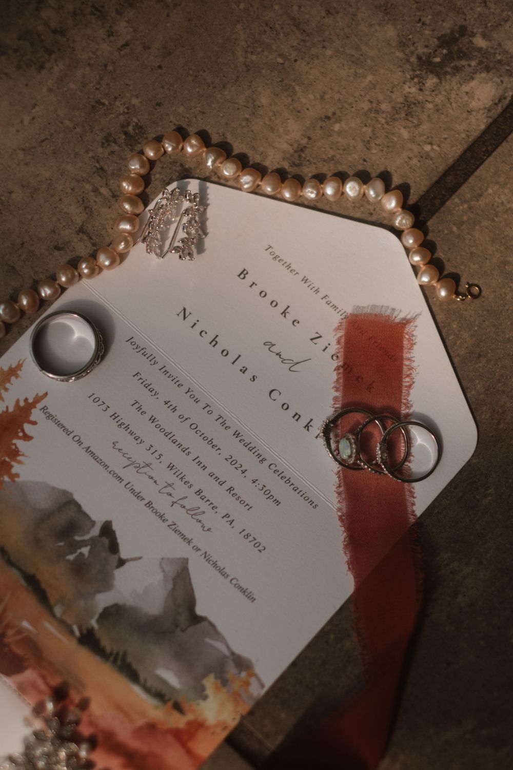 Wedding invitation with pearl details and wedding rings captured in vintage style.