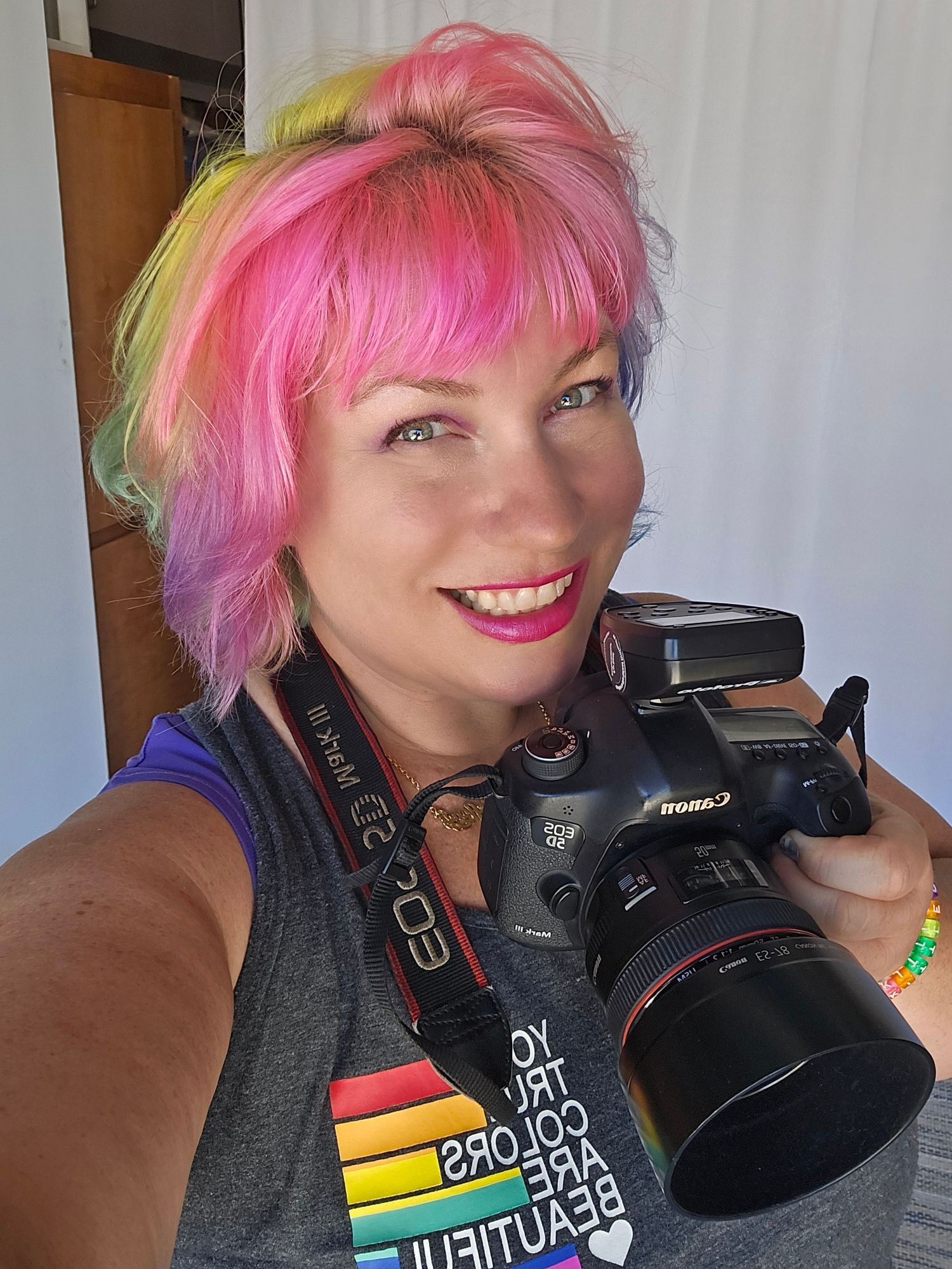 Hot pink dress with matching hair and statement gold necklace against tropical print background.