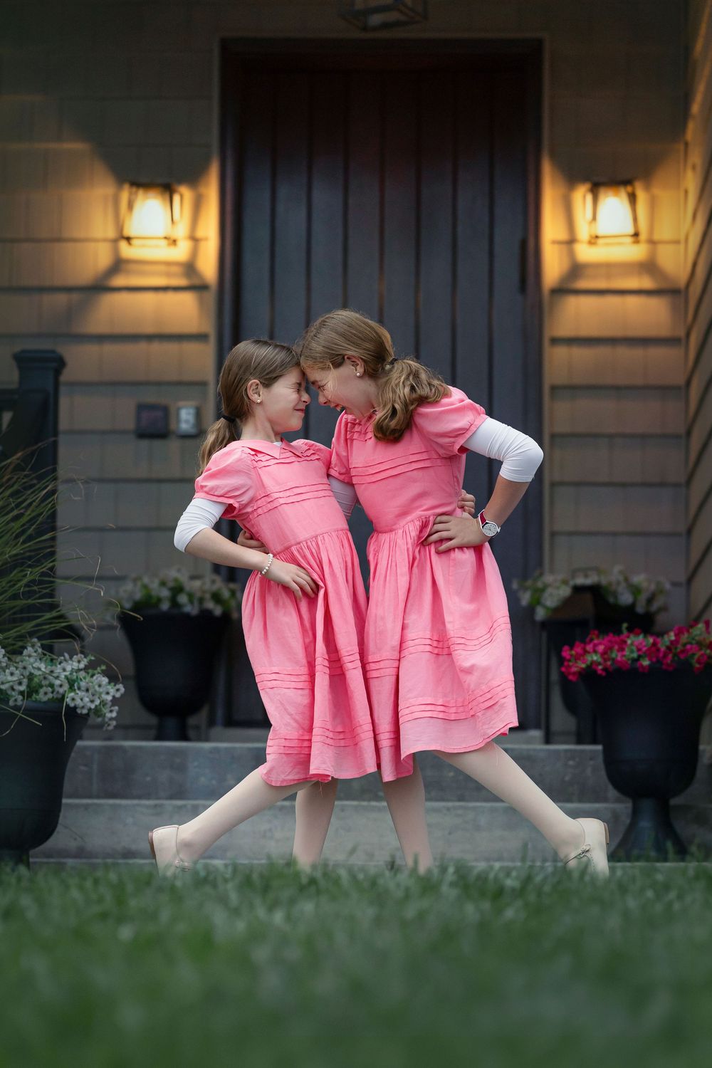 Heartwarming series of two young girls in matching pink dresses playing together outside at dusk.