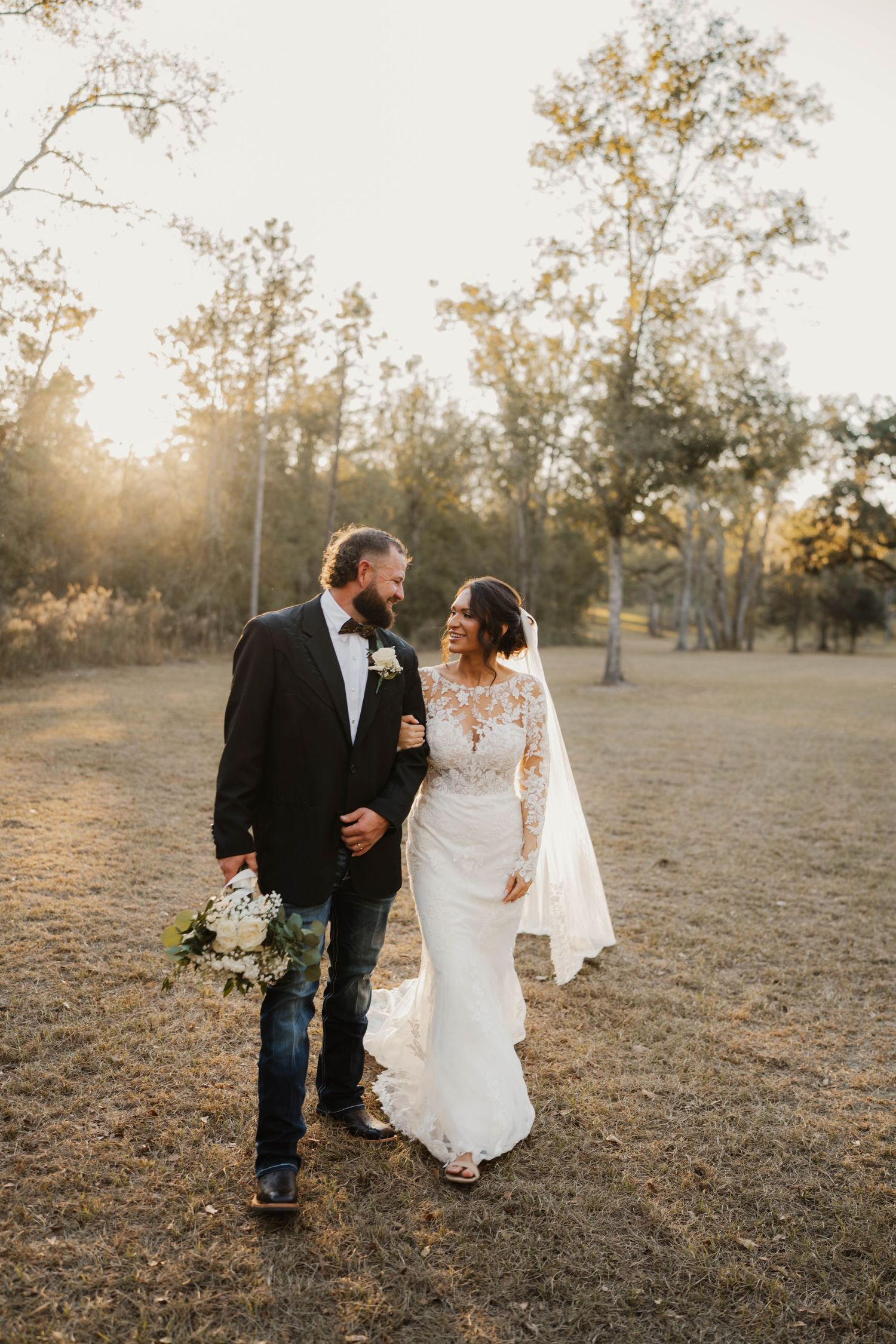 Western-themed wedding couple sharing intimate moment under flowing veil.
