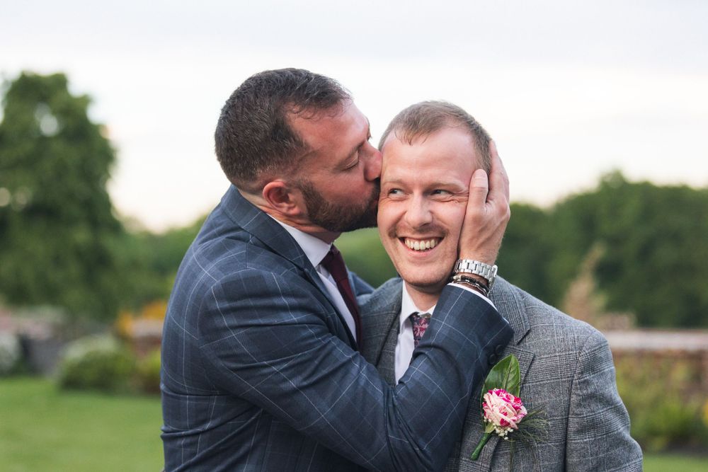 Groomsman kissing groom East Court