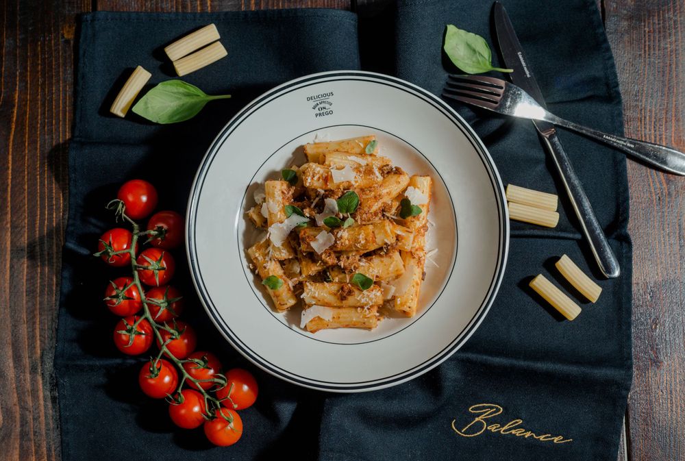 Pasta dish with cherry tomatoes and garnish served on white plate with navy napkin.