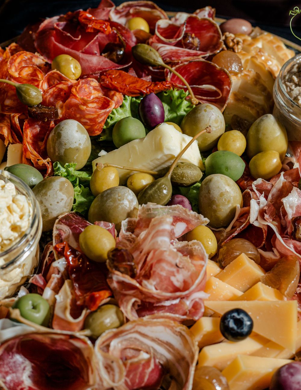 Gourmet charcuterie board with meats, cheeses, olives and accompaniments.