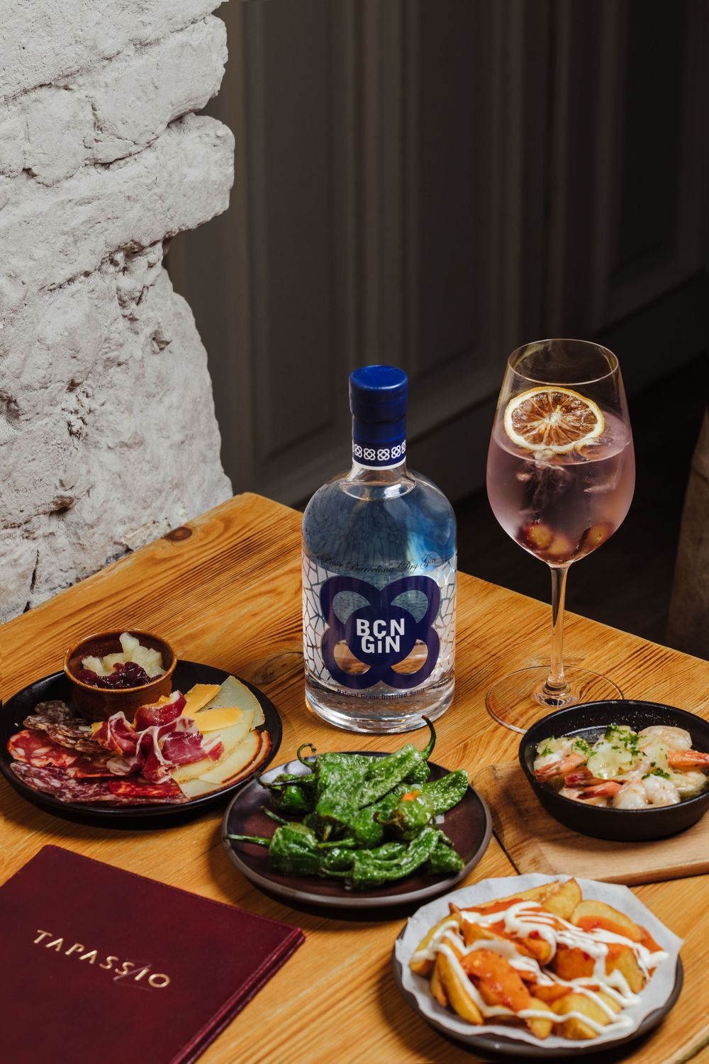 Restaurant table setting with blue gin bottle, cocktail and various appetizer plates.