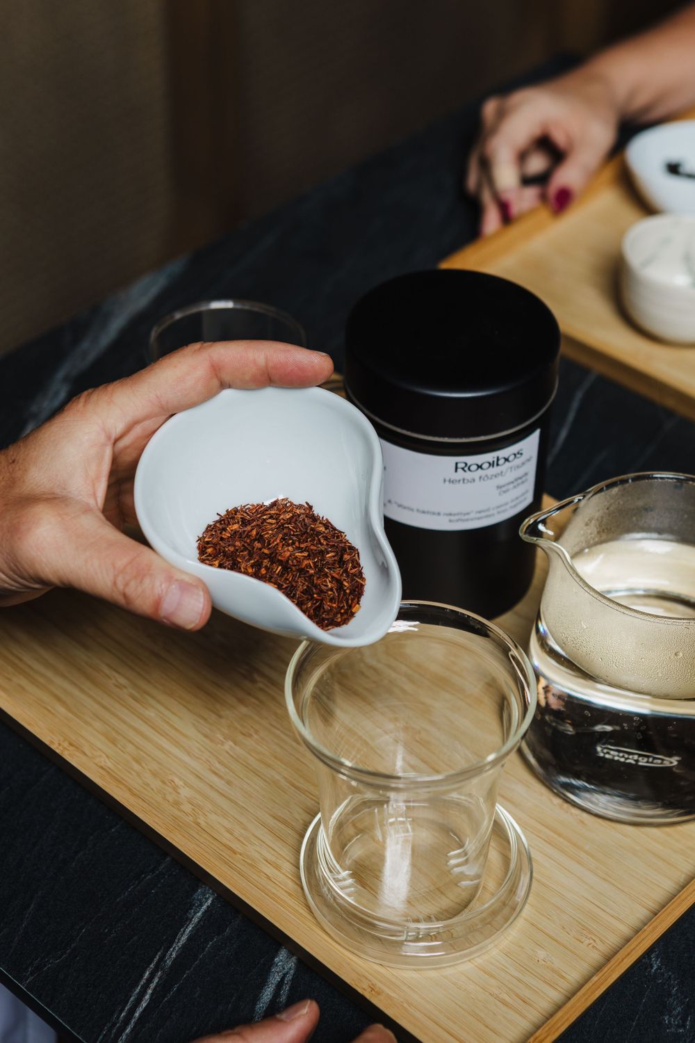 Measuring loose tea into ceramic vessels during traditional tea preparation.