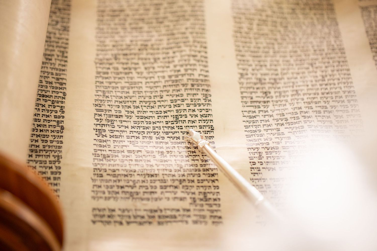 Close up of Bar Mitzvah boy's hand holding the yad as he points to the Hebrew text on the scrolls of the torah - Bar Mitzvah Photography