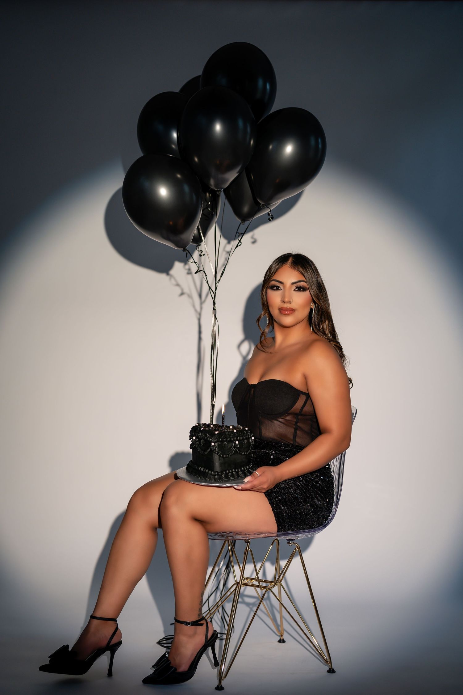 Glamour shot with black balloons and modern white chair in studio setting.Chicago birthday portrait session.
