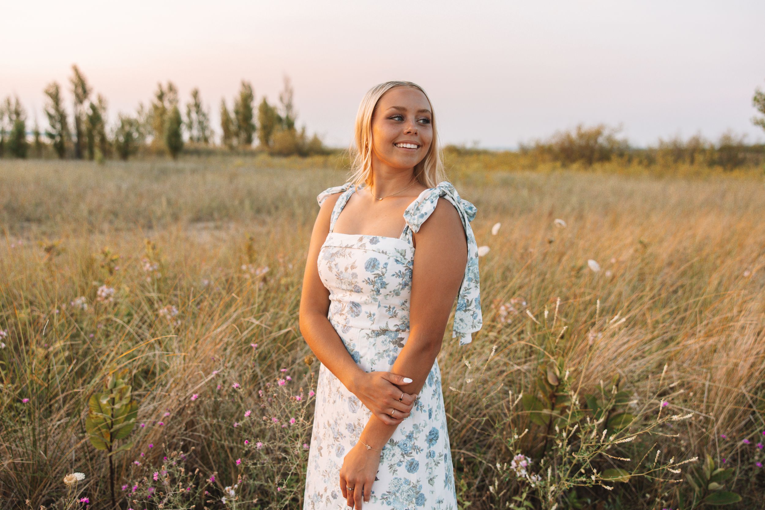 Golden hour portrait of senior in field wearing floral dress—Carson Suttle Photography.