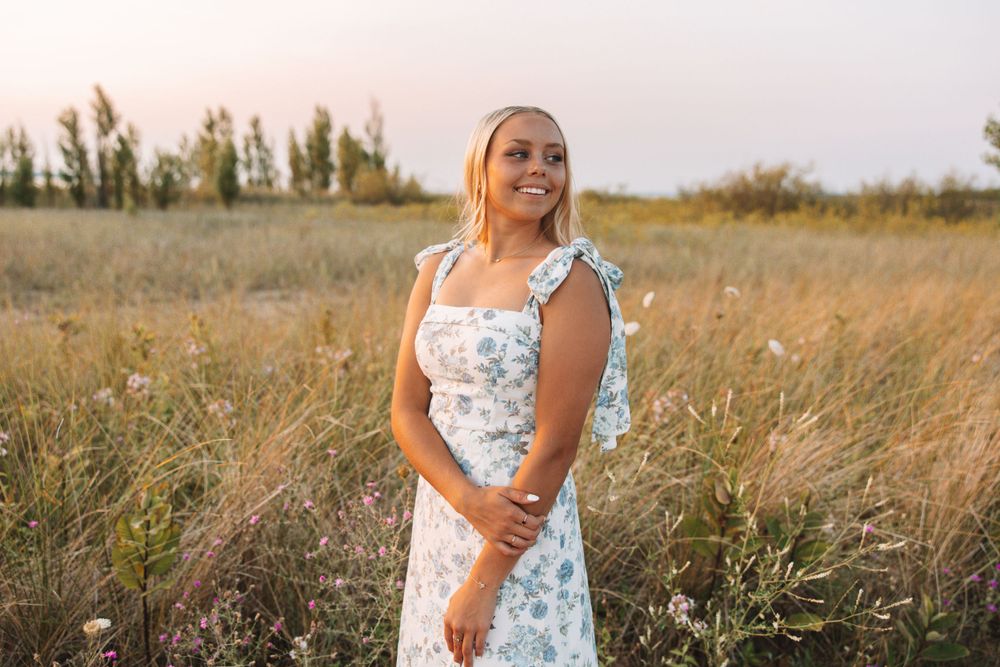 Golden hour portrait of senior in field wearing floral dress—Carson Suttle Photography.