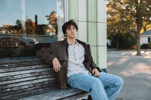 Senior portrait of a young man sitting outdoors in an urban setting during a lifestyle photo session