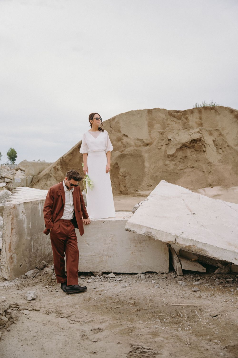 A couple poses artistically against white stone blocks in a quarry setting.