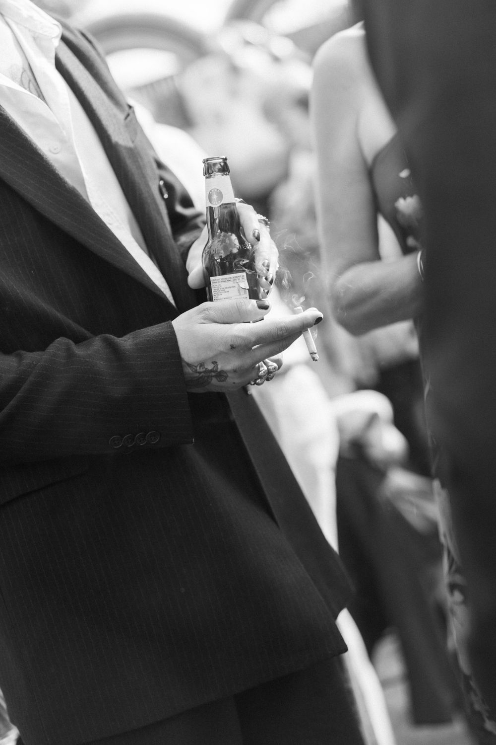 Black and white candid shot of hands holding champagne glasses at a celebration.