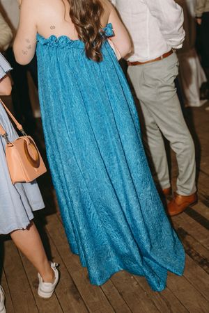 A flowing turquoise blue dress captured in detail on a wooden floor.