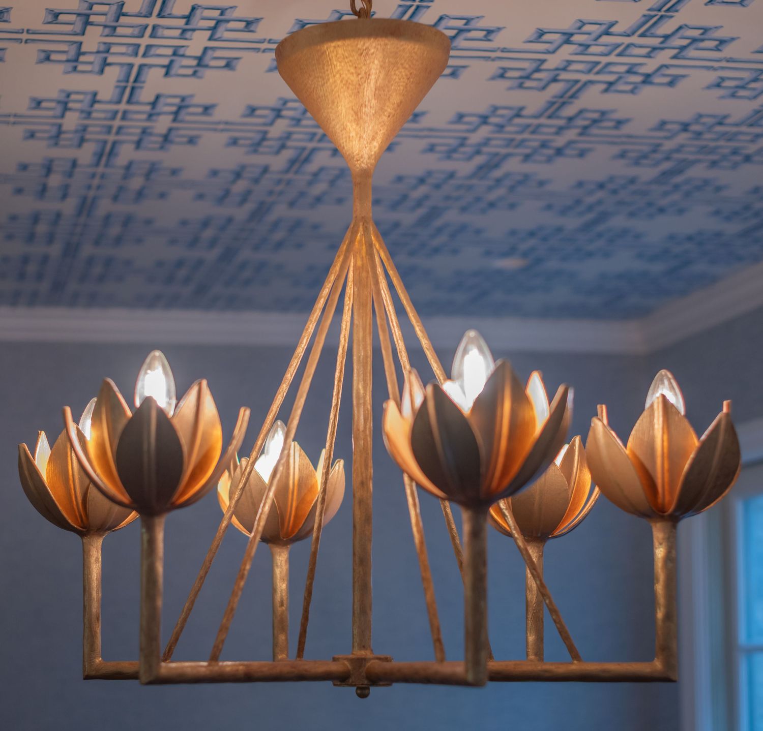 A modern pendant light fixture with metallic copper-colored flower-shaped shades arranged in a linear design.