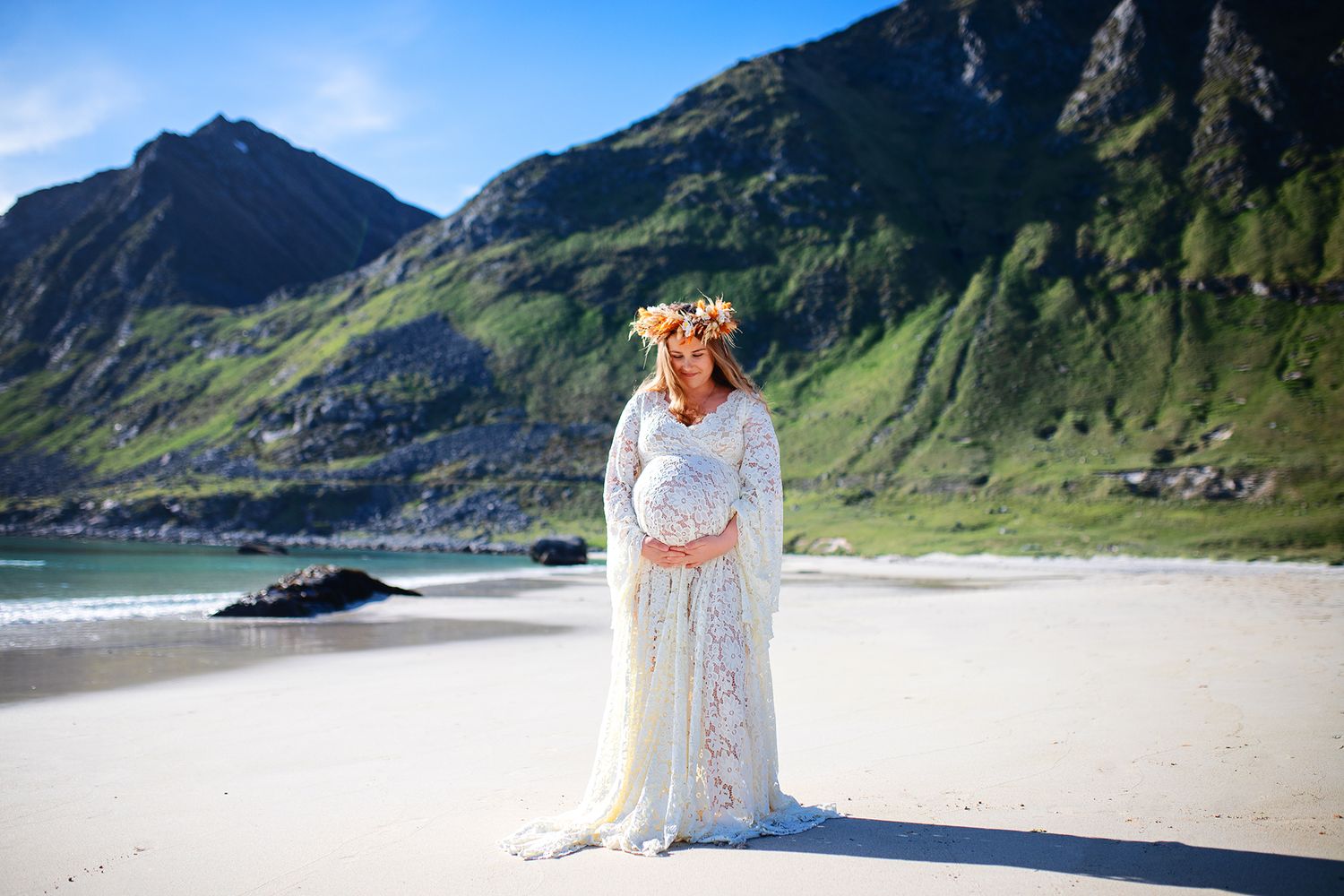 Maternity photoshoot in lofoten, Norway. On a summerbeach in a white maternity dress. Pregnancy photo in Norway.