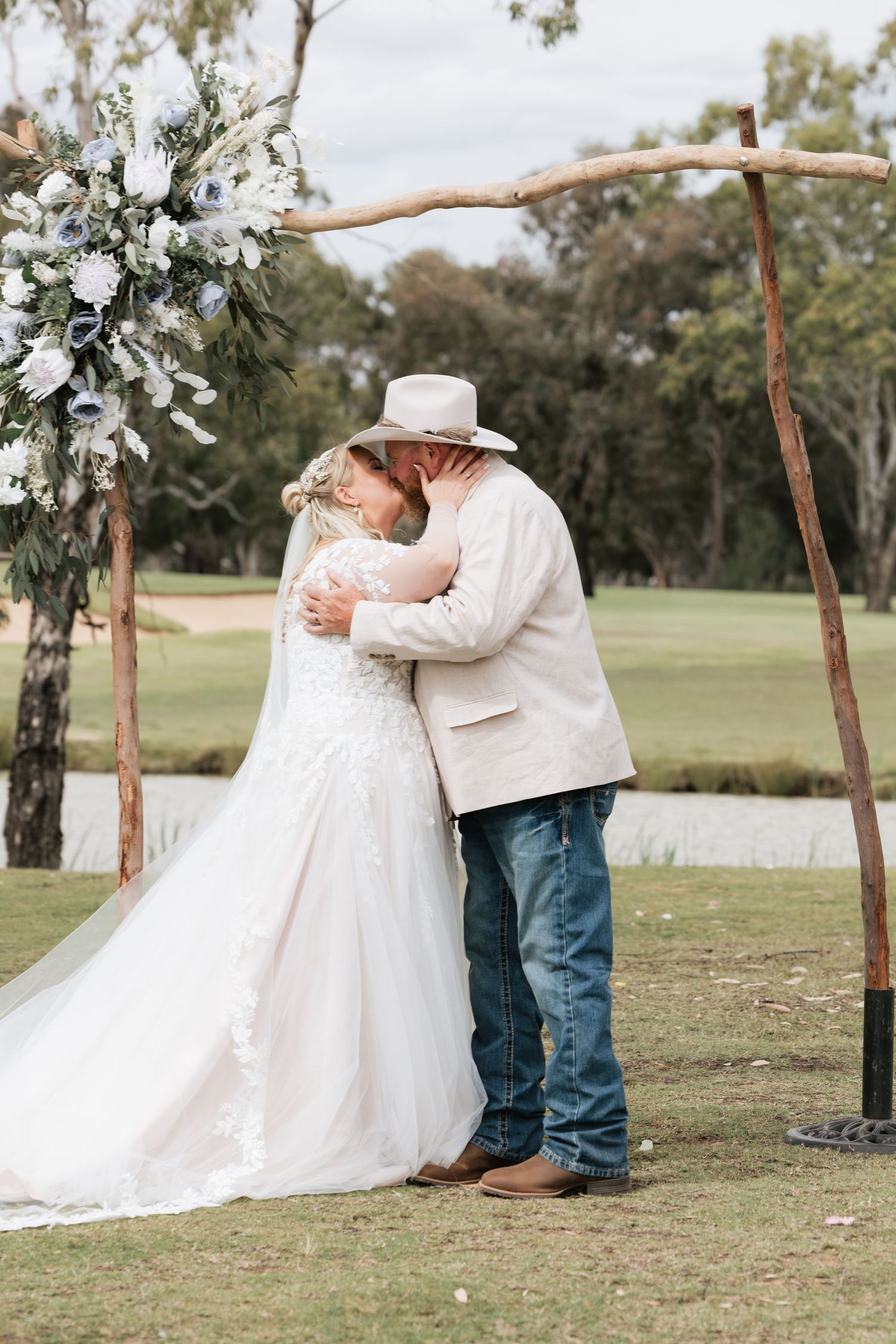 A romantic outdoor wedding moment captured in a series of four photos showing a couple embracing under a floral arch.