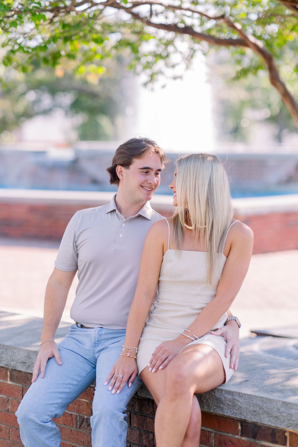 A couple sitting together on a brick wall enjoying a sunny afternoon outdoors.