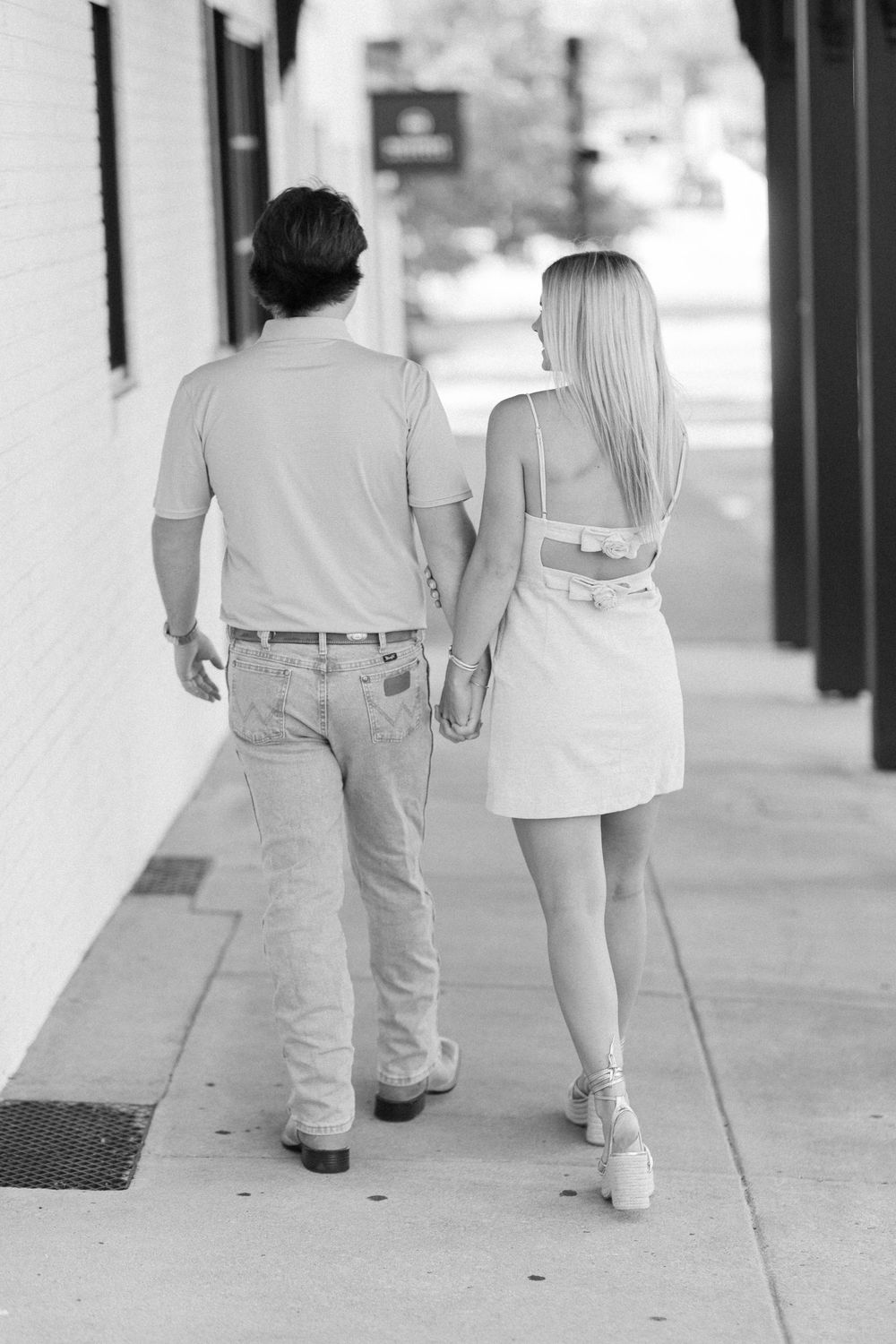 Black and white photo of a couple walking together along a covered walkway.