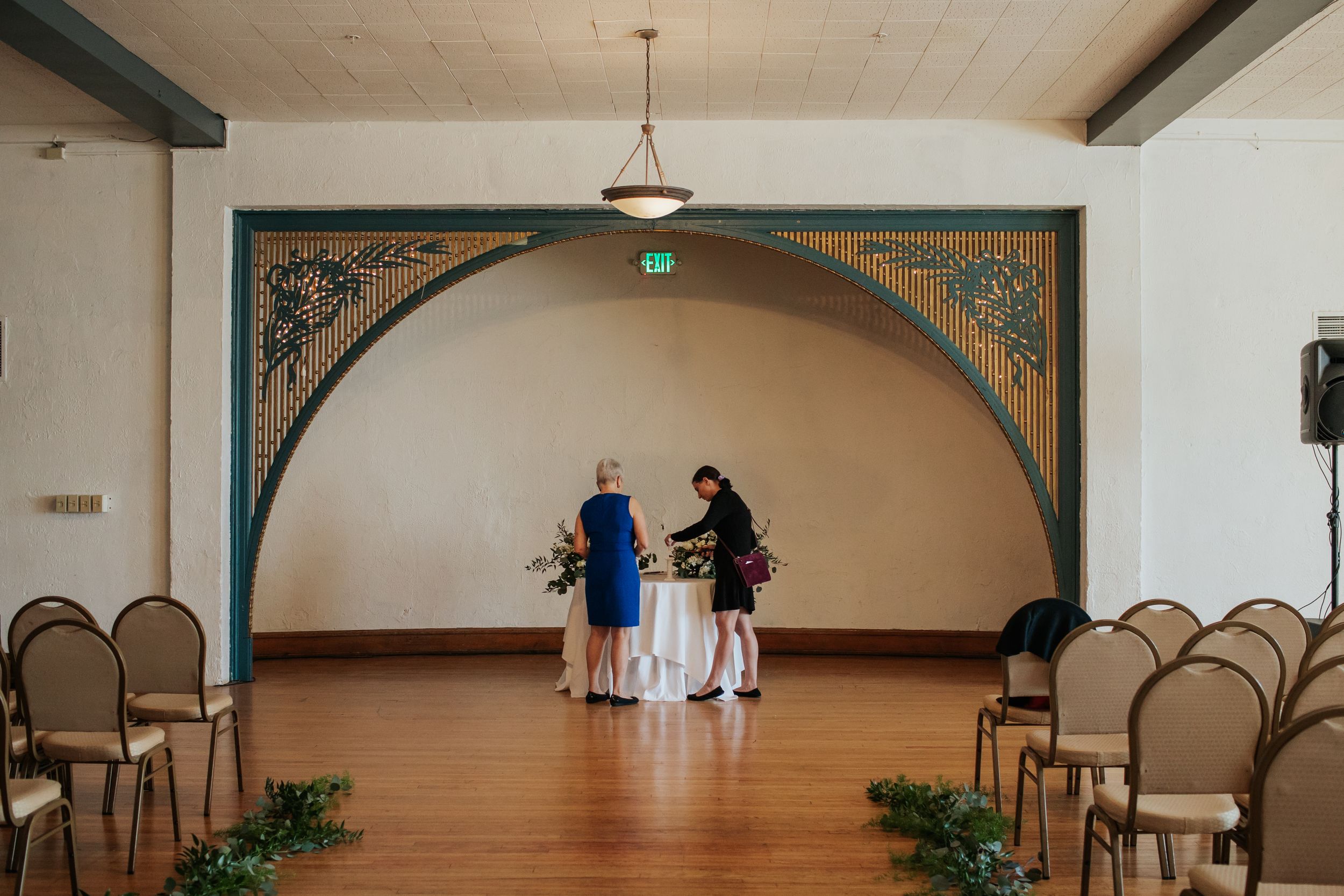 A panoramic view of an elegant event venue with arched doorways, wood beams, and pendant lighting.