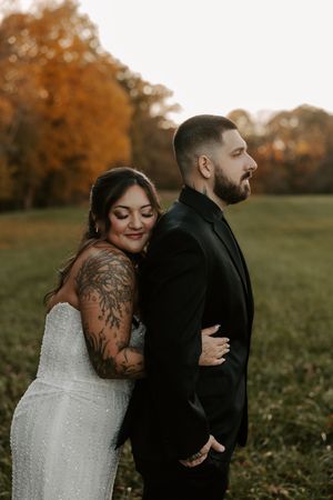 Romantic wedding photography session in a grassy meadow with golden autumn trees.