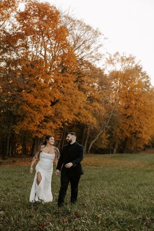 Scenic fall wedding photography with couple framed by golden trees in distance.