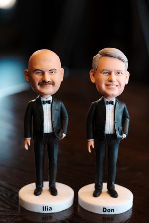 Custom wedding cake toppers featuring two small figurines in black tuxedos standing side by side.