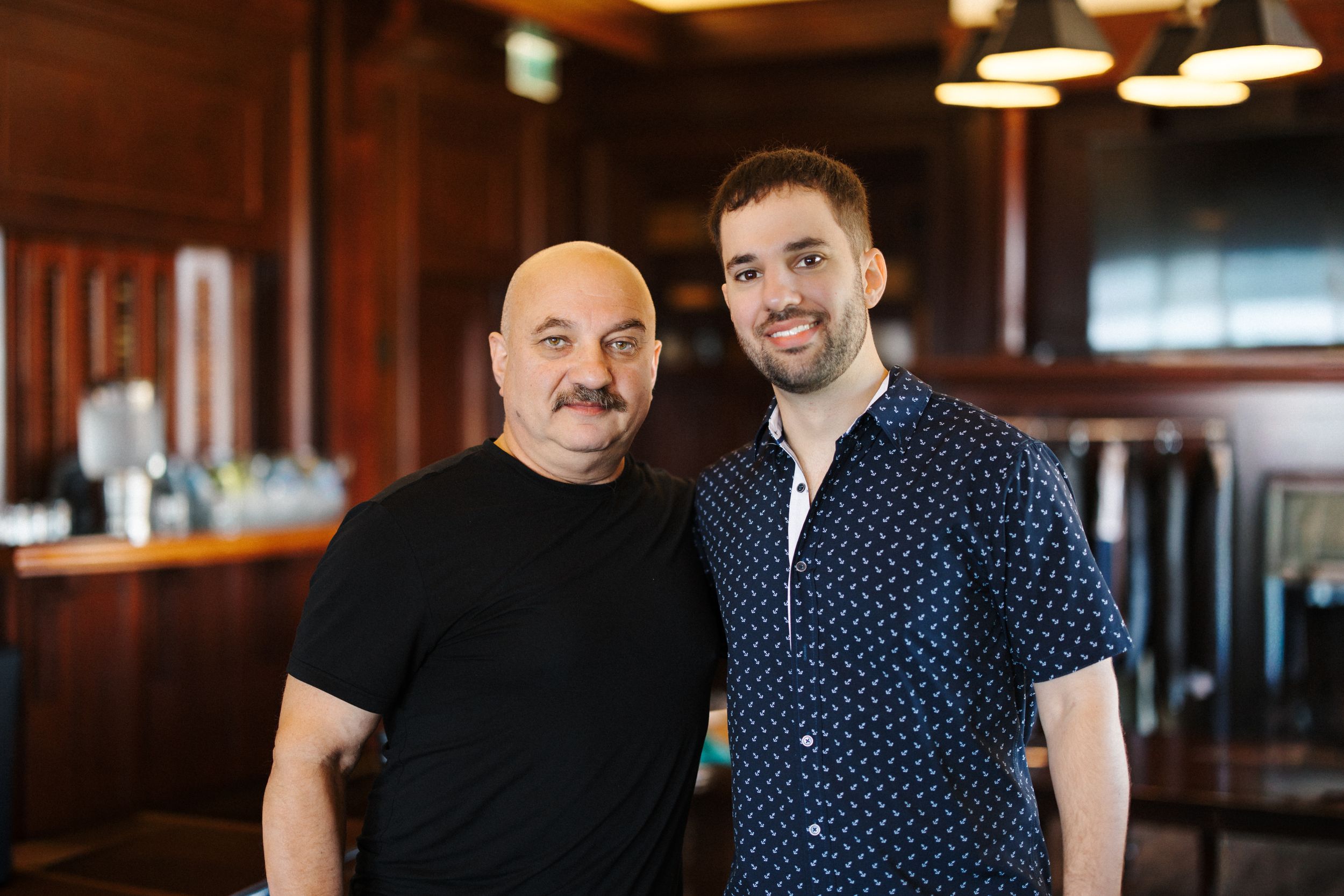 Two business professionals in a modern office setting wearing polka dot and dark colored shirts.