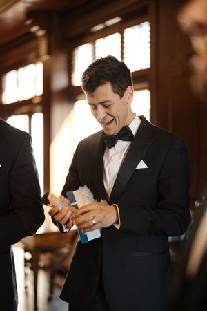 Series of photos showing hands adjusting a black bow tie against a formal tuxedo in warm lighting.