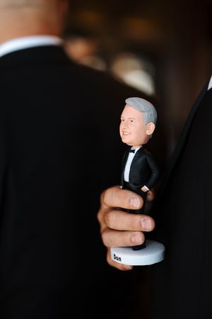 Close-up shots of hands holding and rotating a small white figurine against a dark background.