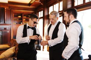 A series of candid moments showing groomsmen getting dressed and helping each other prepare for a formal event.