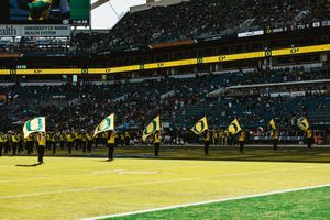 Row of cheerleaders performing on sideline of football field during game at stadium.