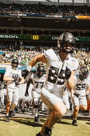 Football team in white uniforms running onto the field during a game.