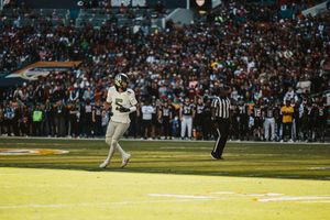 Wide shot of a football game in progress at Hard Rock Stadium with spectators in the stands.