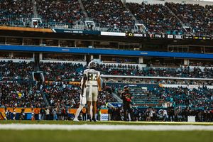 Wide angle view of a football game in progress at a packed stadium.