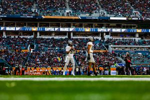 Wide view of a football stadium with teal seats and crowd during a game.