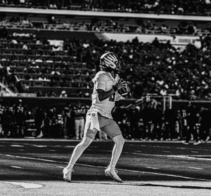 Black and white action shot of players running on football field during game.