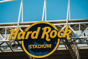 Hard Rock Stadium illuminated sign against bright blue sky.
